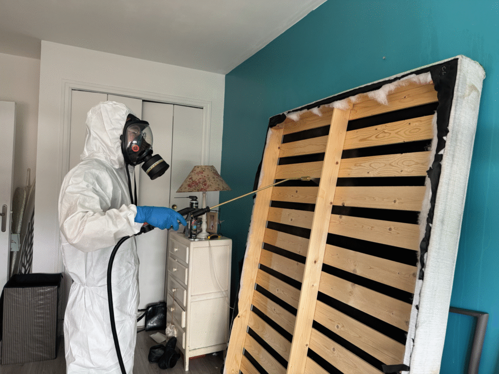 ntervention de désinfection professionnelle haute performance à Paris par un expert Hygiène et Nuisible. Un technicien en combinaison EPI intégrale et masque à gaz applique un traitement biocide par nébulisation dans un appartement pour éradiquer virus, bactéries et agents pathogènes après une infestation. Protection sanitaire garantie.